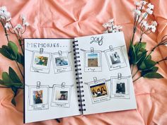 an open notebook with pictures on it and flowers next to it, sitting on a bed