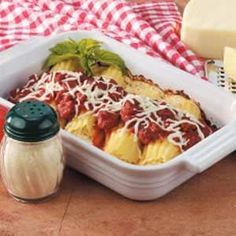 a casserole dish with meat sauce and cheese on the side next to some grated cheese