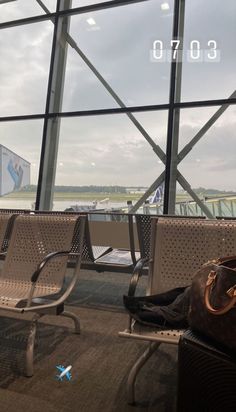 two metal benches sitting next to each other in front of a large window with an airplane on it's side