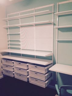 an empty room with shelves, bins and chairs