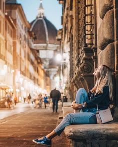 a woman sitting on the side of a building looking up