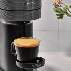 a cappuccino coffee maker on a counter next to a vase with flowers