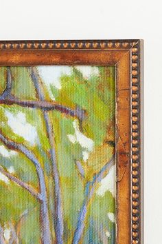 an oil painting of a tree in a frame on the wall next to a white wall