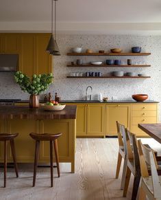 a kitchen with yellow cabinets and wooden stools