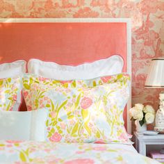 a bedroom with pink and yellow wallpaper, floral bedding and white nightstands