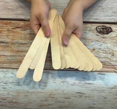 two hands are holding small wooden paddles on a table