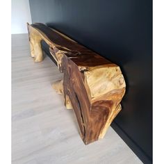 a wooden bench sitting on top of a hard wood floor next to a black wall