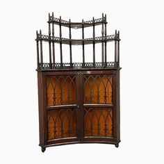 an ornate wooden cabinet with glass doors on the top and bottom, in front of a white background