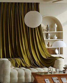 a living room filled with furniture and a green drape covered curtain over the couch