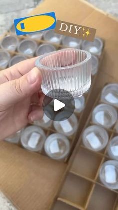 someone is holding a glass in front of an empty box with plastic cups on it