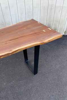 a wooden table sitting on top of a black metal stand in front of a building