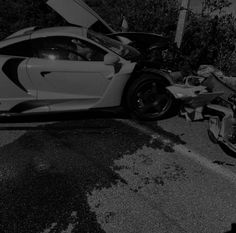 a white sports car with its hood open sitting on the side of the road next to a motorcycle