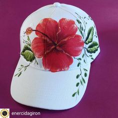 a white baseball cap with red flowers painted on it's front and side panels