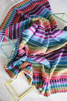 a crocheted blanket sitting on top of a wooden floor next to a chair