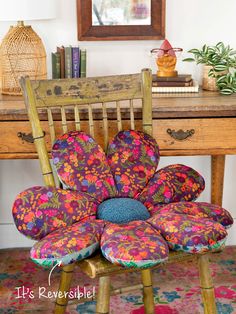 an upholstered chair sits in front of a desk with a flower pillow on it