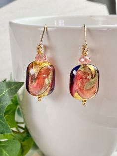 "Hold on tight when you see these Murano earrings in person! The photos just simply do not reflect how stunning these glass beads are. The glass has a subtle purple hue or flash as you look at them in the light. The beads have genuine gold foil within the beads with swirling colors of salmon and sage. A peach colored Austrian crystal accents the bead as they hang on Gold Fill lever back ear wires for wonderful comfort and security. The earrings hang 1.5 inches. These are exclusive beads that I w Fusion Style Czech Glass Jewelry For Gifts, Fusion Style Czech Glass Jewelry Gift, Elegant Earrings With Colorful Beads For Gift, Elegant Glass Dangle Jewelry, Fusion Style Glass Jewelry For Gifts, Unique Glass Jewelry With Matching Earrings, Elegant Dangle Glass Jewelry, Elegant Czech Glass Jewelry With Matching Earrings, Glass Round Beads Earrings As Gift