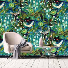 a chair and table in front of a colorful wallpapered room with birds on it