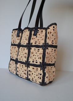 a crocheted tote bag sitting on top of a white table next to a wall