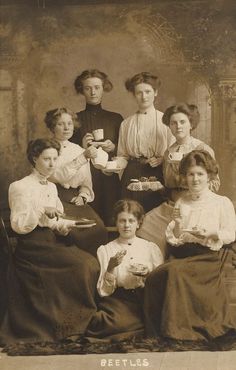 an old photo of women in dresses and holding plates with food on them, posing for the camera