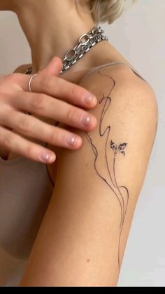 a woman's arm with a tattoo on it and a chain around her neck