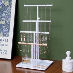 a jewelry stand with earrings and necklaces hanging from it's sides on a wooden table