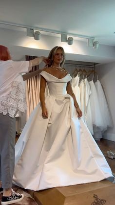 a woman in a white wedding dress standing next to a mannequin and another person