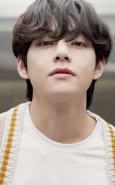 a young man with grey hair wearing a white t - shirt and yellow striped vest