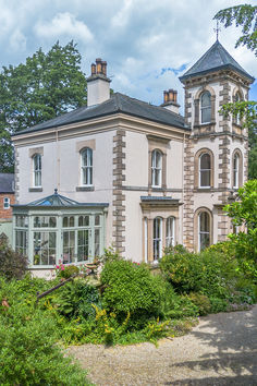 a large white house surrounded by greenery and trees