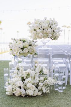 an arrangement of white flowers and chairs on the ground