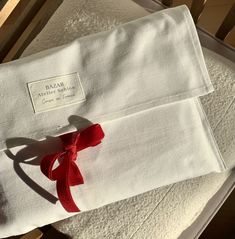 two folded white towels with red ribbon on them