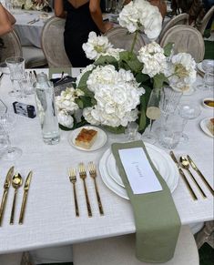 the table is set with silverware and white flowers