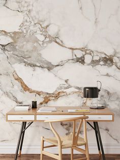 a desk with a lamp and some papers on it in front of a marble wall