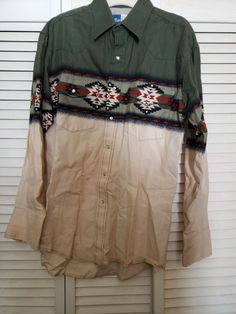 Vintage Wrangler Cowboy Shirt Qith Aztac Markings. This is a vintage 1990 Wranglers Western shirt with pearl covered snaps and Aztec print. The shirt is sized medium and is in great used condition but there is a small stain (see photo) on the left sleeve near the cuff. Vintage Cotton Shirt For Rodeo, Western Style Washed Cotton Tops, Western Long Sleeve Shirt With Graphic Print, Western Style Long Sleeve Shirt With Graphic Print, Western Style Long Sleeve Graphic Print Shirt, Distressed Long Sleeve Tops For Rodeo, Country Style Cotton Shirt For Rodeo, Long Sleeve Washed Tops For Rodeo, Country Style Long Sleeve Cotton Shirt