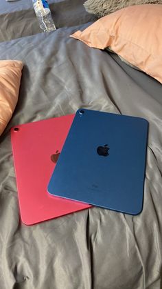 three different colored ipads sitting on top of a bed