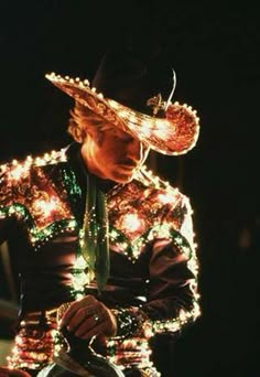 a man dressed in an elaborate outfit with lights on his head and hands holding a steering wheel