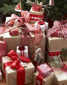 many wrapped presents under a christmas tree with red ribbons and bows on them, all stacked together