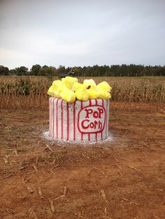 a popcorn box cake with yellow frosting and pop corn on the top in a field