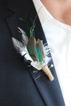 a man wearing a suit and tie with feathers on it's lapel pin