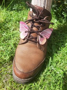 a person wearing brown boots with pink butterfly decorations on the side of their shoe laces