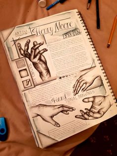 an open book with pictures of hands and writing tools on it, next to some pens