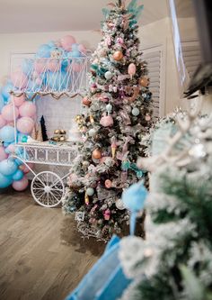 a decorated christmas tree in a living room next to balloons and a white cart filled with presents