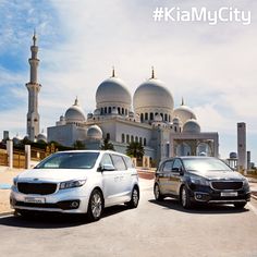 two cars parked next to each other in front of a large white building with domes