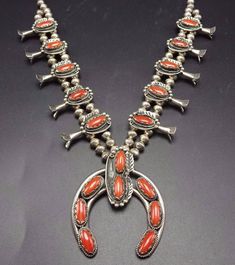 "VINTAGE NAVAJO SQUASH BLOSSOM NECKLACE DESCRIPTION: This stunning necklace features 18 oval cabochons of old red Mediterranean coral. The gemstones are secure in scalloped bezel, on a foundation of heavy gauge vintage sterling silver. Each blossom is framed with an applied leaf, applied raindrops, and a sterling silver swirl. This magnificent necklace will be a valuable addition to your collection of fine vintage Native American jewelry. MEASUREMENTS: Necklace measures 26\" end to end Naja meas Red Antique Collectible Jewelry, Vintage Red Round Jewelry, Red Heirloom Jewelry For Collectors, Red Oval Victorian Necklace, Red Vintage Necklace With Cabochon, Vintage Red Cabochon Necklace, Red Vintage Jewelry With Cabochon, Vintage Oval Red Jewelry, Red Vintage Cabochon Necklace