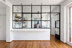 an empty room with wooden floors and glass walls on the wall, along with a white counter