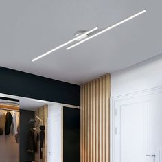 an open closet with clothes on hangers and lights above it in a modern room