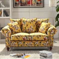 a living room with a yellow floral couch and bookshelves on the wall behind it