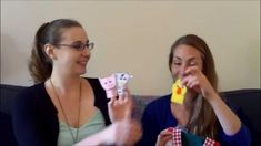 two women sitting on a couch playing with small toy animals in front of each other