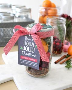 a jar filled with fruit and nuts on top of a white counter next to oranges