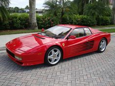 a red sports car is parked on the side of the road in front of palm trees