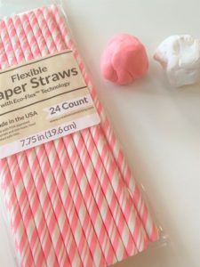 pink and white striped paper straws next to two cotton candy balls on a table